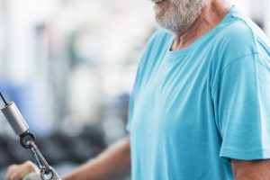 one mature man lifting a weight with a machine at the gym - active senior training hard